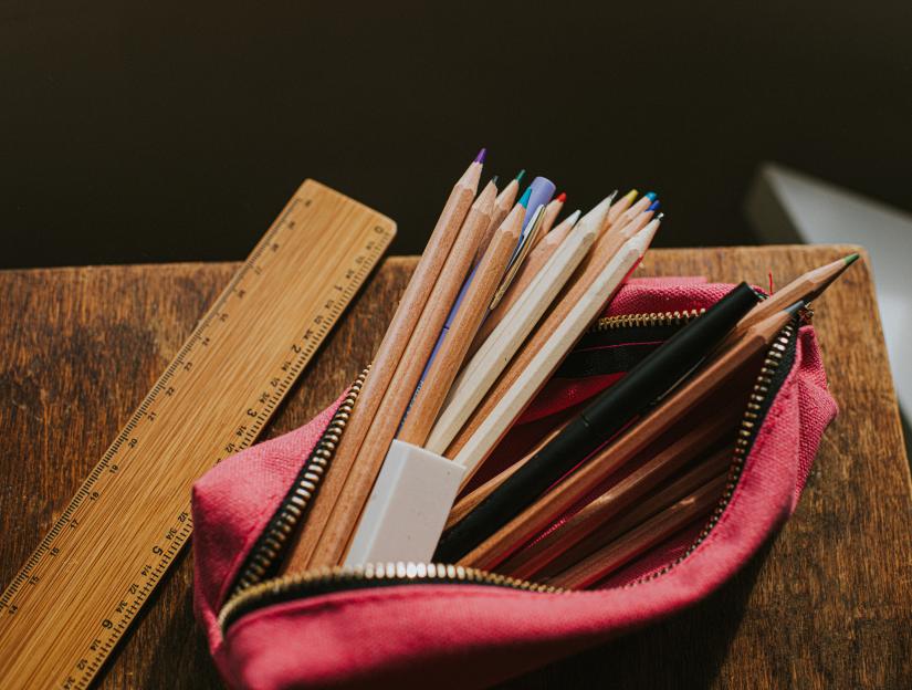 Pink pencil case with pencils, pens, an eraser, and a ruler.