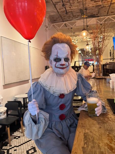 Ed Sheeran in a Pennywise costume holding a red balloon and a pint of beer.