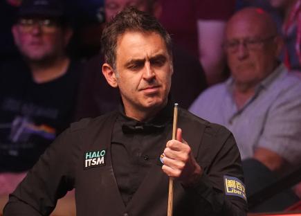 Ronnie O'Sullivan at a snooker match, looking at his cue.