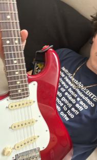 Person holding a red electric guitar.