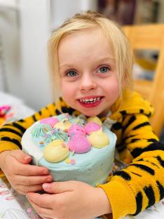 A young girl holding a decorated birthday cake.