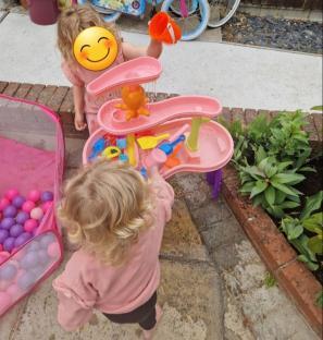 Two toddlers playing with a pink water table.