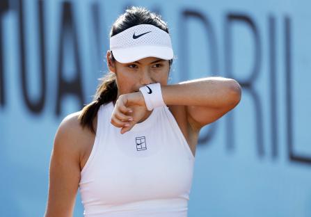 Emma Raducanu wiping her face during a tennis match.