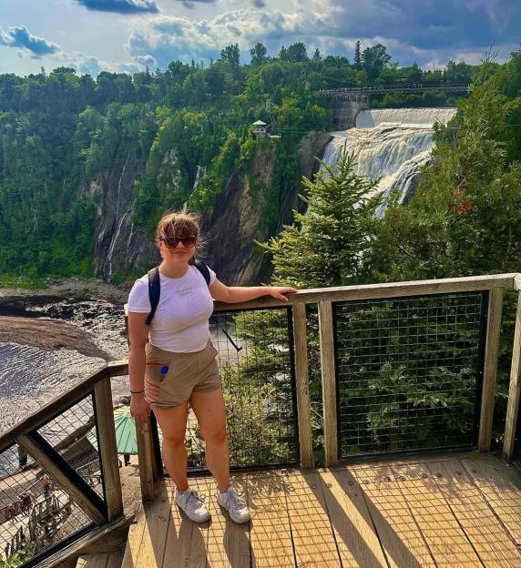A woman standing on a wooden deck overlooking a waterfall.