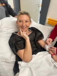 Woman smiling in hospital bed after surgery.