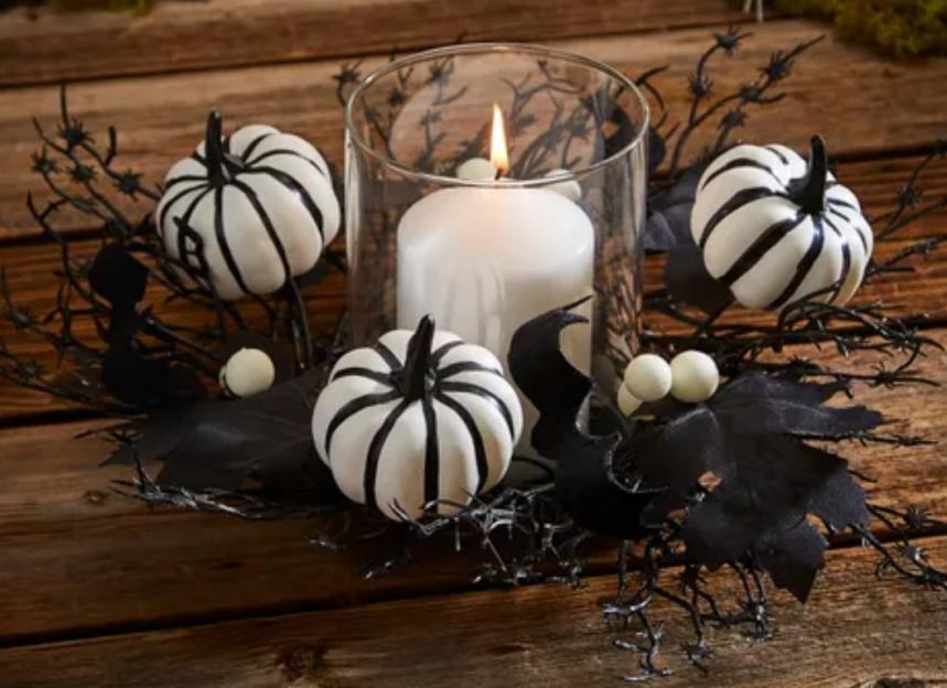 Halloween centerpiece with black and white pumpkins and a candle.