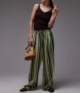 Woman wearing brown tank top and striped pants.