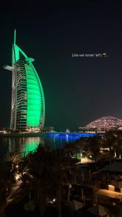 Night view of the Burj Al Arab Jumeirah in Dubai, lit in green.