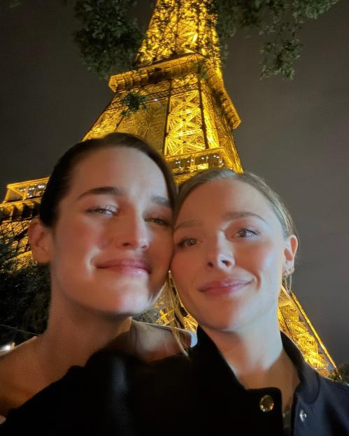 Selfie of two women in front of the Eiffel Tower at night.