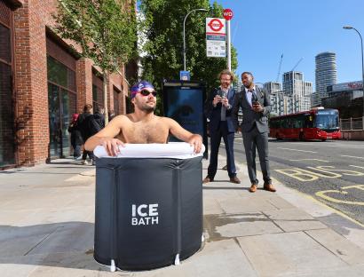 Man taking an ice bath at a bus stop.