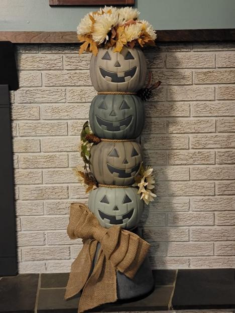 Stacked jack-o'-lanterns with flowers and burlap bow.