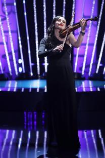 A woman in a black dress playing a violin on stage at the BAFTA Television Awards.
