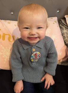 Photo of Archie Squire, a one-year-old boy, wearing a grey sweater with a