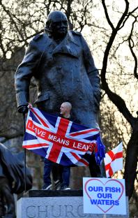 Pro-Brexit protester on Winston Churchill statue holding a flag that says