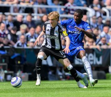 Anthony Gordon of Newcastle United and Moises Caicedo of Chelsea battling for the ball during a Premier League match.