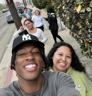 A selfie of a man and several women on a sidewalk.