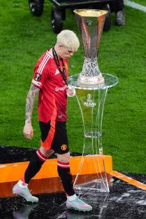 Alejandro Garnacho of Manchester United walks past the UEFA Europa League trophy.
