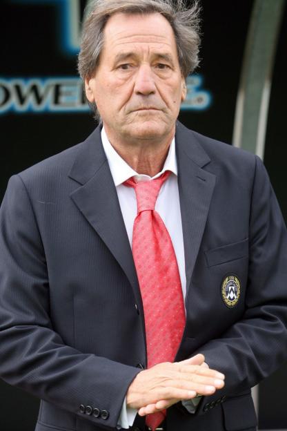 Francesco Guidolin in a suit with a red tie and a badge on his left lapel.