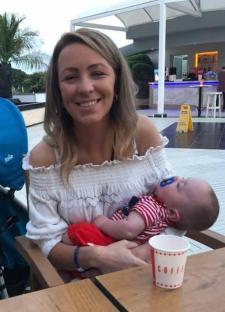 Woman holding sleeping baby at outdoor cafe.