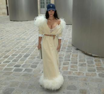 Kim Kardashian wearing a beige feather-trimmed coat and baseball cap.
