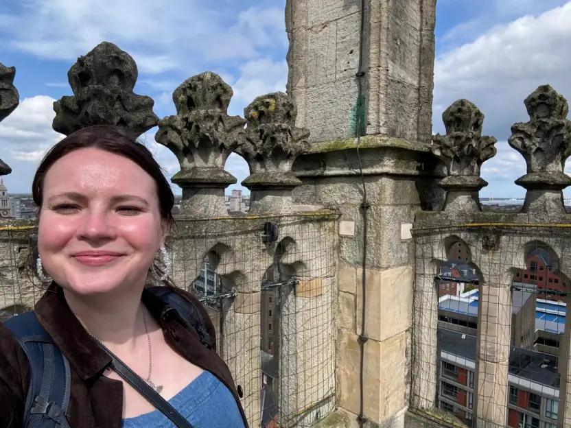 A woman smiles in a selfie from the top of Hull Minster's tower.