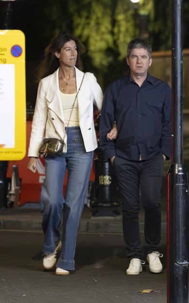 Noel Gallagher and Sally Mash walking arm in arm at night.