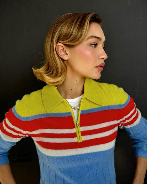 Gigi Hadid in a striped yellow, red, white, and blue zip-up polo sweater.
