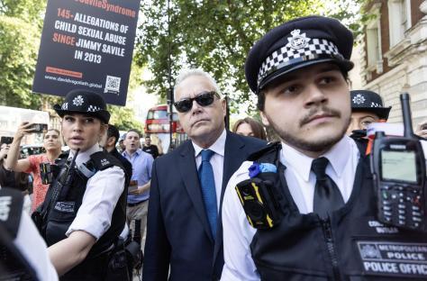 Huw Edwards arriving at court, surrounded by police and protestors.