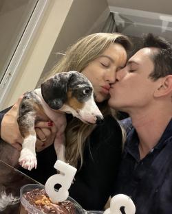 Couple kissing with their dog and a birthday cake.