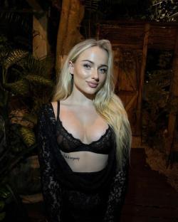 Woman with long blonde hair wearing a black lace bra and robe.