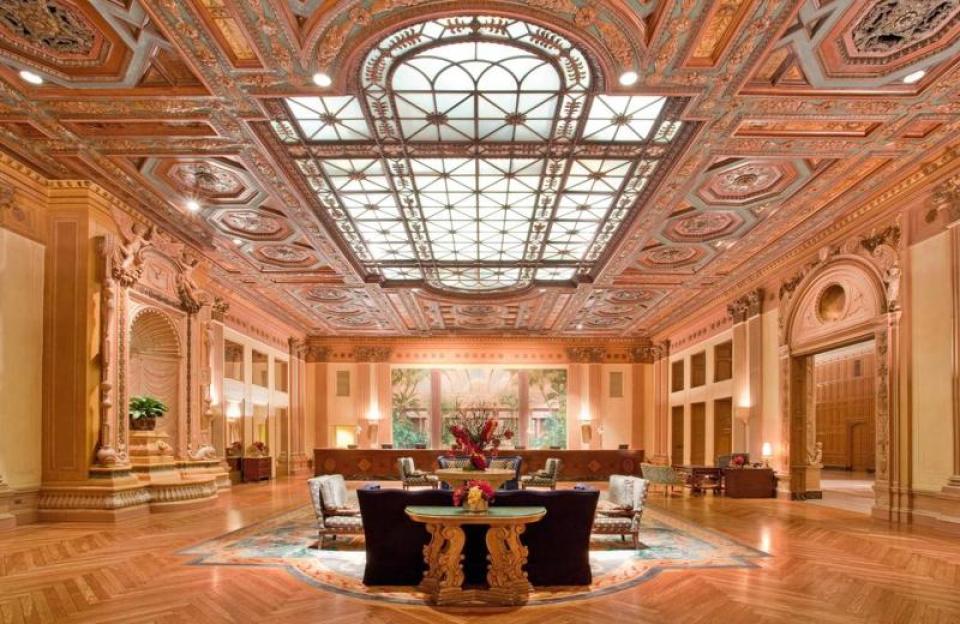Lobby of The Baltimore Hotel with ornate ceiling, large skylight, wooden floors, and seating areas.