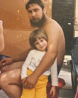 Photo of a shirtless man holding a young child.