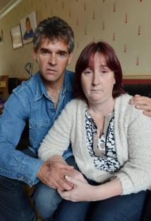 Parents holding hands, grieving the murder of their daughter.