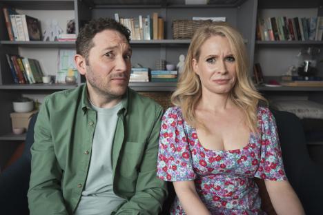 a man in a green shirt and a woman in a floral dress are sitting next to each other