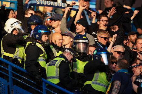 Police officers monitoring Djurgarden fans at a soccer match.
