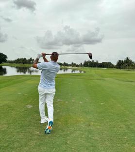 Golfer teeing off on a golf course.