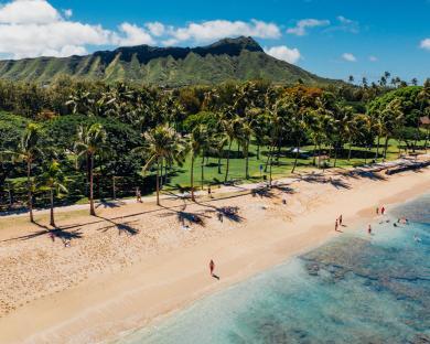 Aerial view of a Hawaiian beach with people swimming and relaxing.