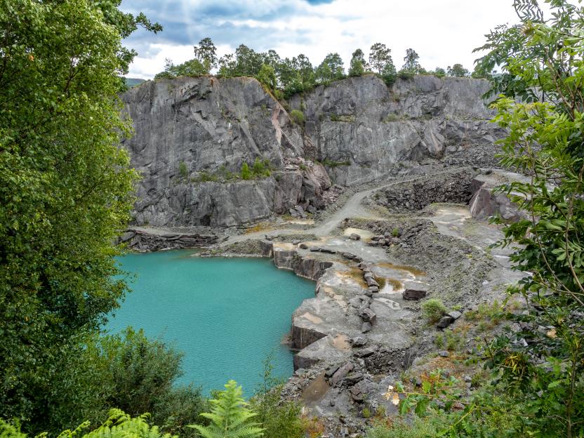 Elterwater quarry in Langdale valley, England with a bright blue pond.