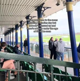 A mostly empty race track grandstand with a few older people; a young woman in a short dress sits in the foreground.