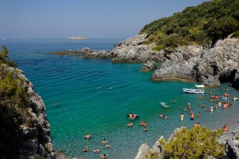 People swimming and relaxing at a rocky beach in Maratea, Italy.