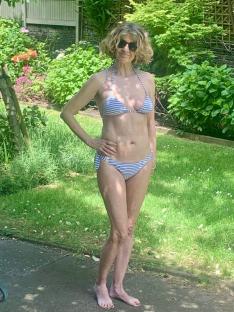 Woman in striped bikini in a garden.