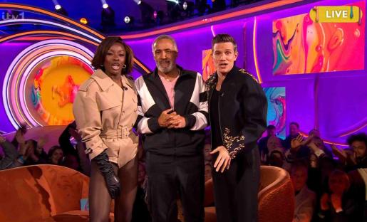 Three people on a game show set.