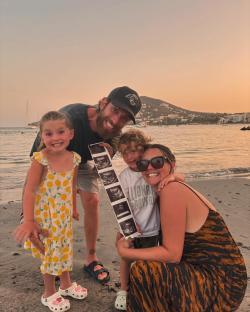 Family on beach holding ultrasound photo.