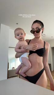 Woman in a swimsuit holding a baby.