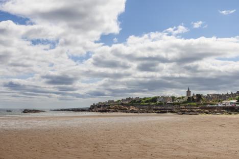 Serene beach in St Andrews, Scotland, with a view of the town's historic skyline.