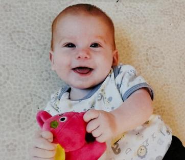 Smiling baby holding a stuffed animal.