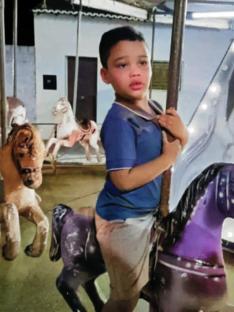 A young boy with autism rides a carousel horse.
