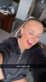 A very happy girl with sparkly makeup and braided hair.