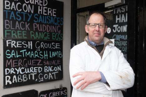 Butcher standing outside his shop.