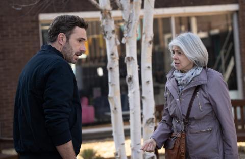 A man and a woman talking outdoors.